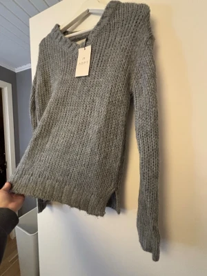 Grå stickad tröja från ADPT - Mysig grå stickad tröja från ADPT med slit.