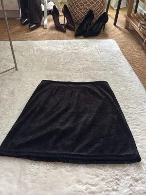 Svart sammetskjol med dragkedja - Säljer en svart kortkjol i mjuk sammet med en diskret dragkedja bak. Snygg att matcha med både boots och klackar. Från machallie, står ingen storlek men skulle nog passa någon som vanligtvis bär storlek XS