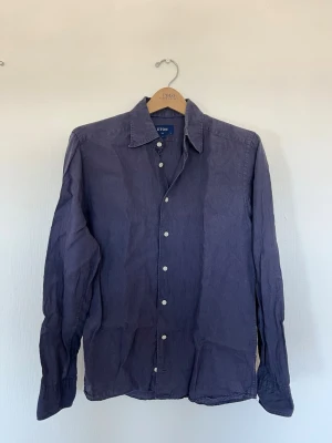 Blå linneskjorta från Eton - Snygg blå skjorta från Eton i linnematerial med klassisk krage och vita knappar. Skjortan har lång ärm och en slim passform som ger en clean och modern look. Perfekt för dig som gillar stilrena plagg med hög kvalitet.