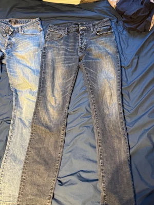 Blå slim fit jeans från Neuw - Snygga blå slim fit jeans från Neuw med klassisk femficksdesign och slitna detaljer. Jeansen har en tvättad look med ljusare partier och kontrastsömmar. Perfekta för en avslappnad och trendig stil. Materialet är denim i bomull.