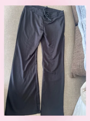 Lågmidjade Svarta utsvängda mjukisbyxor - 🩷Säljer ett par svarta mjukisbyxor med utsvängda ben och dragsko i midjan. Byxorna är i mjukt och stretchigt material, perfekta för chill dagar. Inga synliga loggor eller märken. Passar dig som gillar en relaxed och bekväm stil.💗använd fåtal gånger 