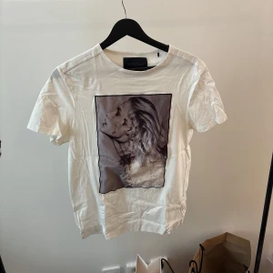 Vit t-shirt med tryck från Limitato - Säljer en vit t-shirt från Limitato med ett coolt tryck av ett konstnärligt motiv på framsidan. T-shirten har en normal passform och är kortärmad, perfekt för en avslappnad stil. Materialet känns mjukt och skönt mot huden.