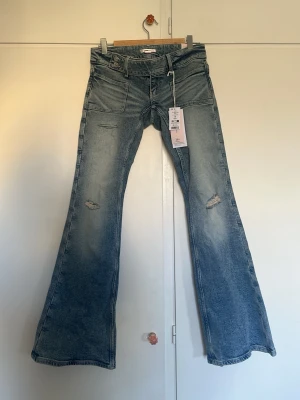 Ljusblåa flared jeans med slitningar - Säljer ett par ljusblåa flared jeans från Gina med vintage tvätt och slitningar på knäna. Jeansen har låg midja och flare ben. Perfekta för en trendig och avslappnad look. Jeansen är i storlek S. Helt oanvända med lappen kvar. OBS!! Pris går att diskutera men eftersom dom är helt nya tänker jag inte acceptera skambud