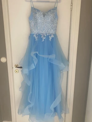 Ljusblå balklänning med glittriga spetsdetaljer🩵 - Pris kan diskuteras vid snabbt köp!!💗                         Helt ny och oanvänd drömmig ljusblå balklänning med tunna axelband, vacker spets upptill och volangig kjol i flera lager. Klänningen har snörning i ryggen och en elegant, flytande siluett som ger en sagolik känsla. Säljer den då den inte passar mig!💗 Kontakta mig om ni vill ha fler bilder eller undrar över något💗