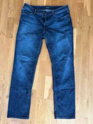 Blå regular fit jeans från Jack & Jones - Snygga blå jeans från Jack & Jones i modellen Regular/Clark. Klassisk femficksdesign, normal midja och raka ben. Tillverkade i slitstark denim med en cool tvättad look. Perfekta för dig som gillar en avslappnad men stilren stil.