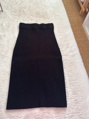 Svart ribbad kjol - Svart ribbad kjol från VILA som går ca till knäna beroende på hur högt man vill att den ska sitta i midjan. Stretchig och jätte skönt material! 