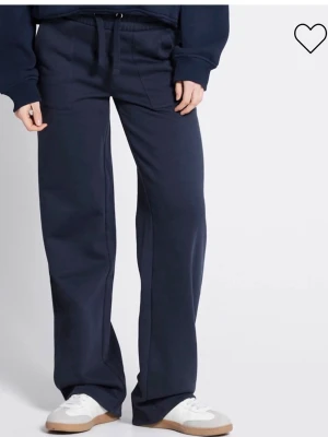 Mörkblå vida mjukisbyxor - Säljer ett par mörkblå mjukisbyxor med raka, vida ben och dragsko i midjan. Byxorna har fickor fram och bak, och är tillverkade i ett mjukt och bekvämt material som passar perfekt för chill dagar. Enkel och stilren design.