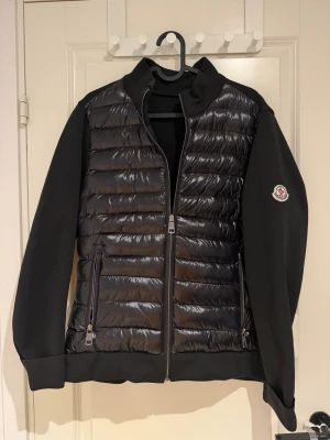 Svart pufferjacka från Moncler - De är i storlek S.  Snygg svart pufferjacka från Moncler med quiltad front och släta ärmar. Jackan har dragkedja framtill, två sidofickor med dragkedja och Moncler-logga på ärmen. Perfekt för kyliga dagar och ger en clean, modern look.