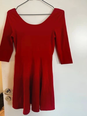 Röd klänning med 3/4-ärm och dragkedja - Snygg röd klänning med 3/4-ärm och rundad urringning både fram och bak. Kjolen är lätt utställd och baktill finns en dekorativ dragkedja. Materialet ser ut att vara mjukt och stretchigt, perfekt för en trendig look. Rök och djurfritt hem. Pruta gärna!🌸