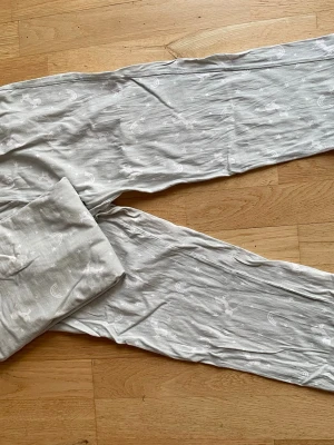  pyjamas  - Mysig pyjamas med långärmad tröja och byxor. Setet har ett gulligt mönster med vita regnbågar, stjärnor och enhörningar. Tillverkad i mjuk bomull, perfekt för chillkvällar hemma. Köparen står för frakt.