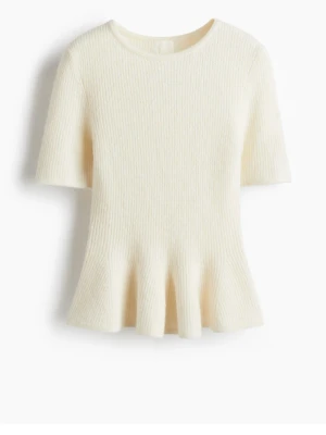 Vit stickad topp med kort ärm - Säljer en krämvit stickad topp med korta ärmar och rund hals. Toppen har en figurnära passform upptill och en lätt utsvängd, pepluminspirerad nederdel. Ribbstickad struktur ger en mjuk och stilren look. Perfekt till jeans eller kjol.