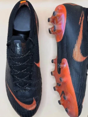 Nike Mercurial Vapor fotbollsskor - Säljer ett par svarta och orange Nike Mercurial Vapor i storlek 42. Inga synliga eller större skador på skorna så mycket bra skick på de! Skriv för frågor!
