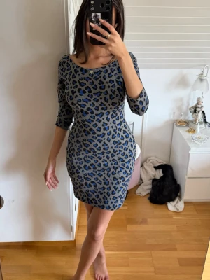 Blå leopardmönstrad mini klänning från Guess - Tight kortklänning med blått leopardmönster från Guess. Klänningen har en rundad halsringning fram och en djupare rygg🤍