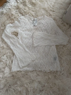 Vit spetstop med långa ärmar - Skir top från H&M. Lätt stretchig, helt i spets. Lätt utställda ärmar. Storlek 170, motsvarar dam XS-S. 