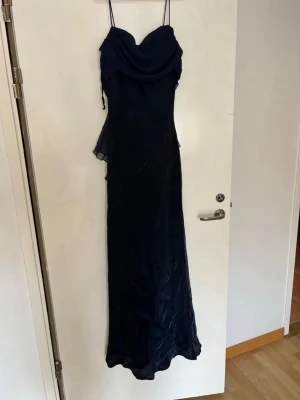 Marinblå långklänning  - en vacker mörkblå långklänning med elegant draperad byst och tunna axelband. Klänningen har ett fint fall i lätt chiffongliknande tyg  Storlek M har suddats ut från lappen dock