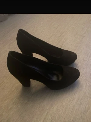 Din sko heels - Snygga svarta pumps med rund tå och bred klack. Skorna har en stilren och tidlös design i mockaliknande material. Perfekta för dig som gillar en enkel men elegant look. Märke och storlek är ej angivet.