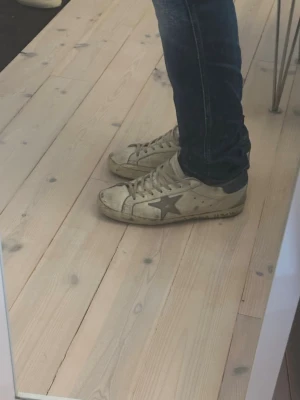 Beige Golden Goose sneakers med stjärna - Golden goose superstar med blå sula storlek 41 passar även 42. Liten defekt på sulan (bild 4) nypris på runt 5500. Box medföljer. Vid snabb affär finns det möjlighet för prutning