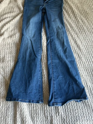 Blå utsvängda jeans med hög midja - Säljer ett par blå jeans med riktigt utsvängda ben och hög midja. Klassisk femficksmodell i mjukt denimtyg. Perfekta för dig som gillar retrostil och vill sticka ut med en cool siluett. Aldrig använt,super trendigt!