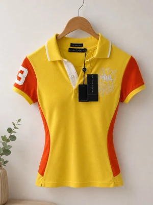Gul och orange pikétröja Ralph Lauren - Sportig pikétröja från Ralph Lauren i gult och orange med vita detaljer. Tröjan har korta ärmar, klassisk krage och knappslå framtill. Stor vit siffra 3 på ärmen och ryggen samt broderad logga på bröstet. Figurnära passform.