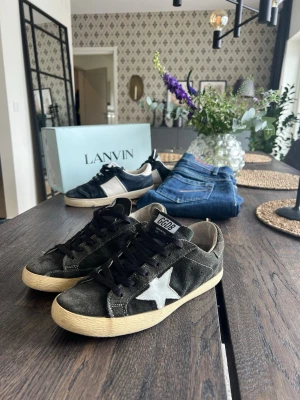 Svarta sneakers från Golden Goose - Snygga svarta sneakers från Golden Goose med vit stjärndetalj på sidan och beige sula. Skorna har svart mocka, svarta skosnören och en klassisk låg siluett. Perfekta för dig som gillar streetstyle och vill ha något unikt på fötterna. Ps defekt på sulan, mwh EA