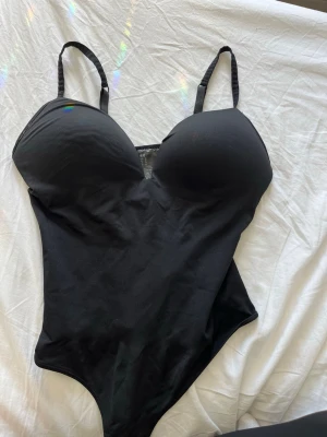 Svart body från H&M - Snygg svart body med vadderade kupor och tunna justerbara axelband. Fint skick från H&M