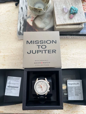 Omega x Swatch MoonSwatch Jupiter -  Säljer min Omega × Swatch MoonSwatch som köptes i Swatch-butiken i Milano 2023, i samband med lanseringen av modellen. Certifikat medföljer.  Klockan är i gott skick med minimala, knappt synliga repor (det finns närbilder för närmare granskning). Den har i övrigt varit väl omhändertagen. Batteriet behöver bytas, vilket är anledningen till det något lägre priset än marknadsvärdet.  Klockan är fortfarande fullt användbar och mycket stilren.  Öppen för bud!