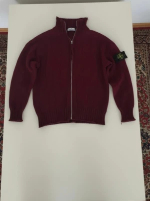 Stone Island - Säljer nu min vinröda Stone Island-kofta i mycket fint skick. Skick: Som ny, sparsamt använd endast ett fåtal gånger. Inga hål eller defekter. Färg: Snygg vinröd färg (Burgundy). Detaljer: Certilogo finns för att bekräfta äkthet (se bild). Klassisk stone island badge på ärmen.