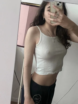 Vit ribbad croppad linnetopp - Snygg vit croppad linnetopp med smala axelband och ribbad struktur. Perfekt för varma dagar och enkel att matcha med olika outfits. Tidlös och stilren design som passar till det mesta.