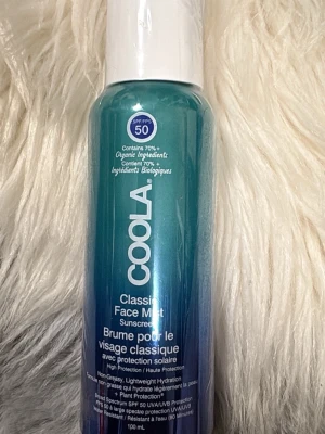 COOLA Classic Face Mist SPF 50 - Fräsch face mist från COOLA med SPF 50, perfekt för att skydda huden mot solen. Innehåller 70% ekologiska ingredienser och ger lätt återfuktning utan att kännas fet. Kommer i en blågrön sprayflaska på 100 ml.