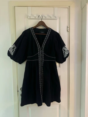 Svart klänning med broderi - skickar idag  - En jättefin svart broderad klänning från indiska. Köpt innan sommaren och den säljs inte längre. Prislappen är borta men den är bara provat på och har tyvärr inte kommit till användning. Normal i storleken och inga skavanker eller något slitage alls🩷🩷 Originalpris ligger på 1299kr  