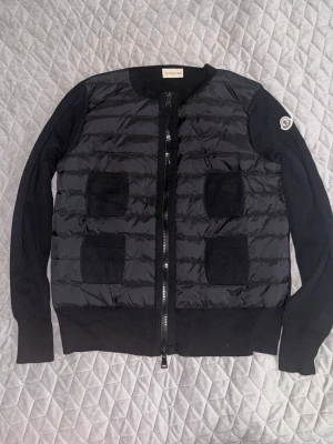 Moncler cardigan dam - ✨ Moncler cardigan – aldrig använd 🤍 Säljer denna superfina Moncler cardigan i nyskick då den tyvärr inte kommer till användning. Väldigt stilren modell som passar perfekt både till vardags och för en mer uppklädd look. Enkel att matcha och ett plagg som verkligen lyfter outfiten ✨  Perfekt nu till våren/sommaren och en tidlös cardigan som funkar säsong efter säsong.  📍Kan mötas upp i Stockholm för smidig och säker affär. Går att diskutera priset vid snabbaffär!