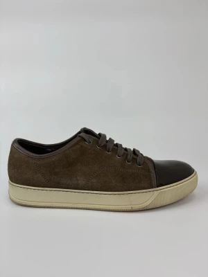 Bruna Lanvin sneakers med lackad tå - Snygga bruna sneakers i mocka med mörkbrun, glansig lackad tå och matchande bruna skosnören. Sulan är vit och ger en klassisk kontrast. Perfekta för dig som gillar en stilren och modern look med unika detaljer.