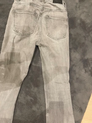Ljusgrå utsvänga byxor från gina tricot  - Säljer mina ljusgrå jeans från gina tricot.Fick i födelsedagspresent men knappt använda eftersom jag inte tyckte dem passade mig.Kan frakta ut när som ungefär.Inga skador på jeansen och ser ungefär som nya ut.
