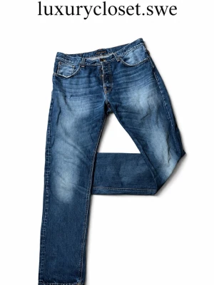 Blå slitna jeans från Nudie Jeans - Priset kan diskuteras! Säljer ett par blå jeans från Nudie Jeans (steady Eddie) som är storlek w38 L36 med snyggt slitna detaljer och klassisk femficksmodell. Jeansen har en rak passform och är gjorda i kraftigt denimtyg med kontrastsömmar. Perfekta för en avslappnad och trendig look.