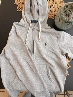 Grå hoodie från Polo Ralph Lauren - Snygg grå zip-hoodie från Polo Ralph Lauren. Storlek small (S). Skriv gärna ifall du har några funderingar🤗