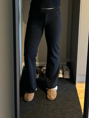 Svarta utsvängda kostymbyxor - Säljer ett par svarta kostymbyxor med utsvängda ben och hög midja. Byxorna har en stilren och enkel design utan fickor eller detaljer. Perfekta för en clean och trendig look. Materialet är mjukt och stretchigt🌟