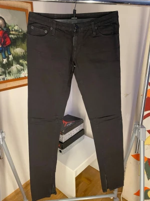 Svarta skinny jeans med dragkedja - Säljer ett par svarta skinny jeans med dragkedja vid benslut och klassisk femficksmodell. Jeansen har låg midja och är tillverkade i stretchigt denimtyg för en tajt passform. Perfekta till en cool och avslappnad stil.
