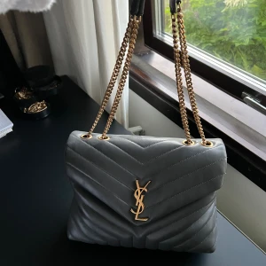 Grå äkta YSL väska - Köpt för 2 år sen. Nypris = 25500kr Kvitto, dustbag och kartong finns. INGA BYTEN! Bredd: 30cm, höjd 25cm och djup 10cm.