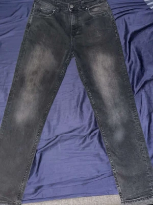 Svarta jeans från Lee med raka ben - Säljer ett par svarta jeans från Lee med raka ben och klassisk femficksdesign. Jeansen har en snygg tvättad look och är tillverkade i bomull. Perfekta för dig som gillar en avslappnad och stilren stil.