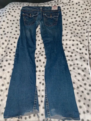 bootcut jeans True Religion - Säljer ett par blå bootcut jeans från True Religion lowwaist från vintage&friends! Storlek W30 står inte längd men skulle säga L30, är 174 brukar bära M i byxor och dom passar mig! Finns slitningar längst ned men inget man tänker på! Kan skicka bild!