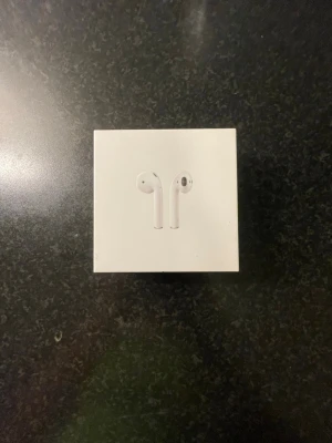 Apple AirPods trådlösa hörlurar - Säljer ett par vita Apple AirPods i originalförpackning. Klassisk stilren design med slimmad form och laddningsetui. Perfekta för dig som vill ha trådlös frihet och snygg look till mobilen eller datorn.