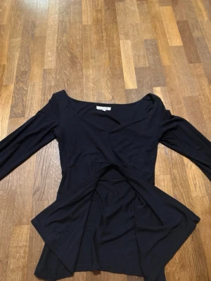 Maddy blouse storlek M/L - Trendig svart omlottopp med lång ärm och v-ringad hals. Toppen har en figurnära passform och är tillverkad i mjukt bomullsmaterial. Perfekt för dig som gillar stilrena och enkla plagg med en twist.