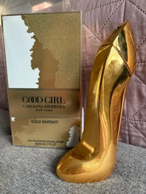 Good Girl Gold Fantasy parfym - Good Girl Gold Fantasy från Carolina Herrera är en lyxig parfym i en unik guldfärgad flaska formad som en högklackad sko. Flaskan är i hård plast med metallicfinish och rymmer 80 ml eau de parfum. Förpackningen är också guldfärgad med elegant design.