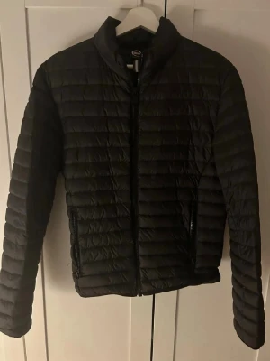 Svart pufferjacka från Colmar - Snygg svart pufferjacka från Colmar med quiltad design och hög krage. Jackan är använd ett fåtal gånger, men fortfarande i fint skick 9/10. Tags finns kvar o skickas med. Jackan passar xs/s
