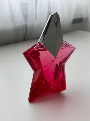 Mugler parfym - Cool parfymflaska i form av en stjärna med starkt rosa glas och silverfärgat spruthuvud. Flaskan har en modern och unik design som verkligen sticker ut på hyllan. Perfekt för dig som gillar snygga detaljer i badrummet. 30 ml se flaska för återstående mängd