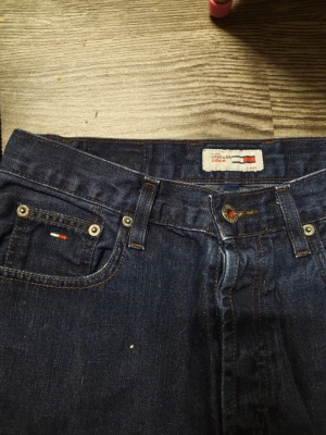Mörkblå raka jeans Tommy Hilfiger Helg REA NU! - Snygga mörkblå jeans från Tommy Hilfiger med raka ben och klassisk femficksmodell. Jeansen har Hilfiger-logga på myntfickan och bak vid linningen. Tillverkade i slitstark denim med snygga kontrastsömmar. Stor rea Nu 