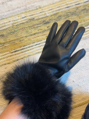 Svarta skinnhandskar med fuskpäls BIKBOK - Stilrena svarta handskar i skinnimitation med bred, fluffig fuskpäls vid handleden. Perfekta för kalla dagar när du vill ha både värme och en lyxig look. Handskarna har en klassisk passform och känns riktigt mjuka.