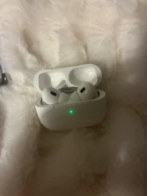 Hörlurar  - Säljer ett par vita EarPods  med trådlöst laddningsetui och tillhörande laddkabel. Snygg och kompakt design i plast, perfekt för dig som vill ha grymt ljud och smidig anslutning till din iPhone eller annan Apple-enhet.