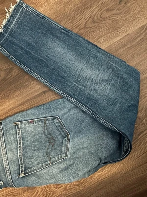 Blå slitna replay jeans - Säljer ett par blå jeans med snyggt slitna detaljer.  Skriv om ni har extra frågor eller vill ha extra bilder! Priset är inte hackat i sten.
