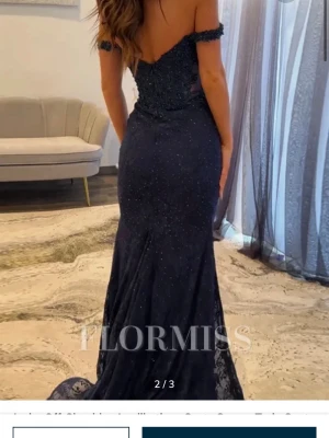 Marinblå långklänning med spets och pärlor - Säljer en marinblå långklänning från Flormiss med offshoulder och figurnära passform.Perfekt för bal eller festliga tillfällen. Klänningen är köpt från Flormiss för 1400kr plus tull och frakt så de landade på ca 2000kr, den är aldrig använd💕